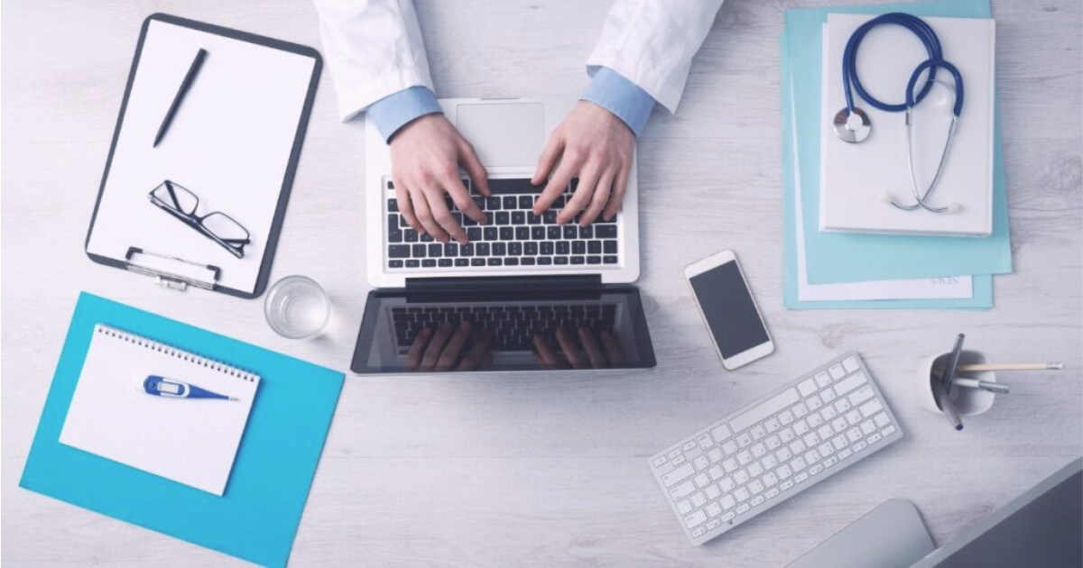 Doctor typing at laptop.